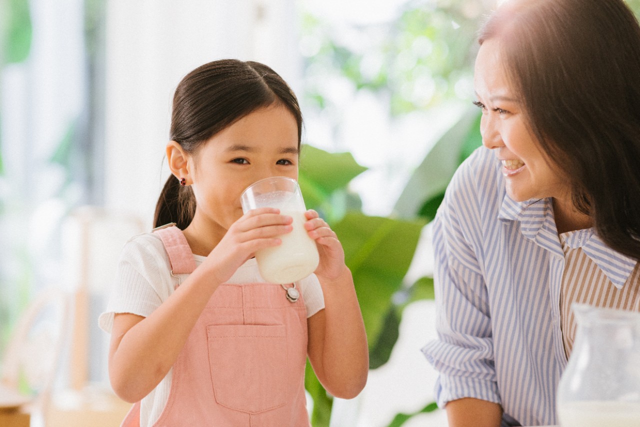 Southeast Asian Mother watching daughter drink milk